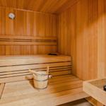 Sauna mit Holzbank, Thermometer und Eimer mit Löffel.