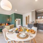 Esszimmer mit Frühstück, Küche und Wohnzimmer mit grüner Wand und Sofa.