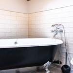Bath with freestanding bathtub, toilet, and tiled wall.