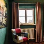 A room with green walls, a colorful chair, and a window with curtains.