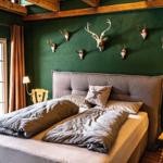 Bedroom with green wall, wooden beams, and deer heads on the wall.