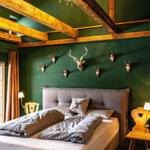 Bedroom with green wall, wooden beams, and deer heads on the wall.