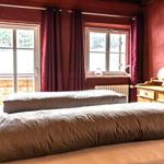 Bedroom with two beds, red walls, and windows with curtains.