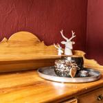 Wooden dresser with silver trays and white deer figures against red wall.