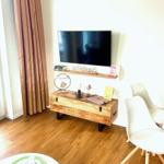 Wohnzimmer mit Fernseher, Holzkonsole und weißen Stühlen