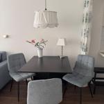 Dining table with three chairs, lamp, and flowers on the table.