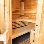 Holzsauna mit Sitzbänken und Temperaturmessgerät an der Wand.