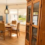 Esszimmer mit runden Tisch, Stühlen und Glasvitrine. Fenster mit Blick auf Garten.