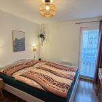 Schlafzimmer mit Bett, Nachttisch, Schreibtisch und Balkontür.