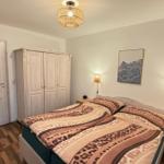 Schlafzimmer mit Doppelbett, Kleiderschrank und zwei Nachttischen mit Lampen.