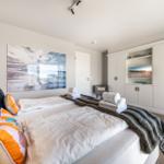 Schlafzimmer mit Bett, Kleiderschrank und Wandbild