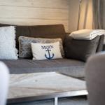 Ein Sofa mit Kissen und Decke vor einem Holzwandpaneel.