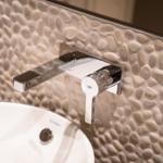 Waschbecken mit modernem Wasserhahn und Steinwand im Badezimmer