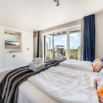 Schlafzimmer mit Blick auf die Strandpromenade und integriertem Fernseher.