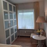 Bedroom with wardrobe, window, armchair, and table.
