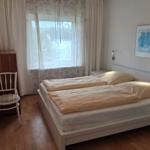 Bedroom with double bed, window with curtains, and chair.