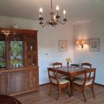 Dining room with wooden table, chairs, sideboard, and chandelier.