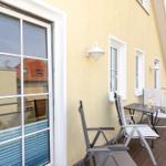 Terrasse mit Tisch, Stühlen und Flasche. Gelber Hauswandschutz mit Fenstern.
