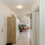 Flur mit Holzschrank und Blick in Wohnzimmer mit Sofa und Tisch