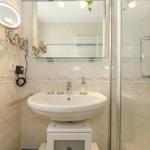 Badezimmer mit Waschbecken, Spiegel und Dusche.