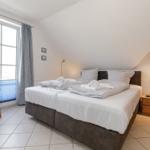 Schlafzimmer mit Doppelbett, Fenster und Nachttisch.