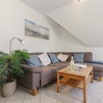 Wohnzimmer mit Sofa, Couchtisch und Pflanze unter schrägem Dach