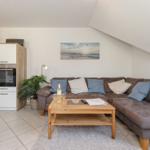 Wohnbereich mit Sofa, Couchtisch und Küchenzeile unter Dachschräge