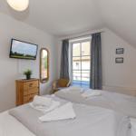 Zimmer mit Doppelbett, Fernseher, Spiegel und Fenster mit Blick.