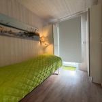 Bedroom with bed, wall art, and wood floor. Door leads outside.