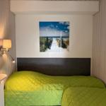 Bedroom with bed, wall art, and lamps on wood wall.