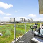 Terrasse mit Sitzgelegenheiten und Blick auf den Hafen und Grünflächen.