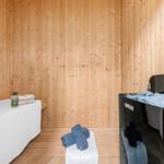 Sauna mit Holzwand, Bank, Steine und Handtüchern.