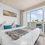Schlafzimmer mit Balkon und Meerblick. Bett, Wandbild und Terrasse sichtbar.