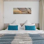 Doppelbett mit blauen Kissen und Musterdecke unter Wandbild mit Segelboot.