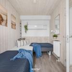 Zwei Betten mit blauen Decken, Holzwände und Wandbilder in einem Schlafzimmer.