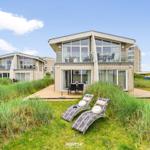Moderne Villa mit Terrasse und Liegestühlen in Grasland