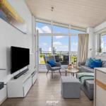 Wohnzimmer mit Fernseher, Kamin und Blick auf den Hafen.