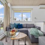 Ein Wohnbereich mit grauem Sofa, Glas-Tisch und Balkonansicht.