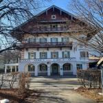 Ein mehrstöckiges Gebäude mit Balkonen und grünen Fensterläden. Eingangsbereich mit Bogenfenstern.