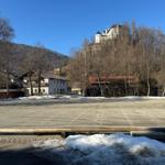 Parkplatz mit Schneehaufen und Blick auf Burg im Winter.