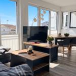 Wohnzimmer mit TV, Esstisch und großem Fensterblick auf Balkon.