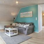 Wohn- und Essbereich mit Sofa, Tisch und Stühlen unter Holzdecke.