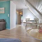 Wohn- und Essbereich mit Sofa, Tisch und Stühlen unter schrägem Dach