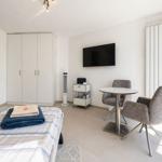 Schlafzimmer mit Bett, Kleiderschrank, Fernseher und Sitzgruppe.