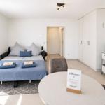 Schlafzimmer mit Bett, Schrank und runden Tisch. Willkommen-Schild auf Tisch.