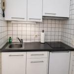 Küche mit weißen Schränken, schwarzer Arbeitsplatte, Spüle und Induktionskochfeld.