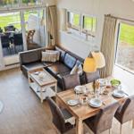 Wohn- und Essbereich mit Sofa, Tisch und Sitzgelegenheiten. Große Fenster und Terrasse.