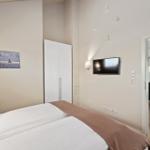 Schlafzimmer mit Bett, Kleiderschrank und TV. Durchgang zur Essnische mit Tisch und Stühlen.
