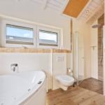 Bad mit Whirlpool, Dusche und Sauna. Holzdecke und Fenster mit Blick.