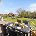 Terrasse mit Esstisch, Stühlen und Blick auf Garten und Häuser.